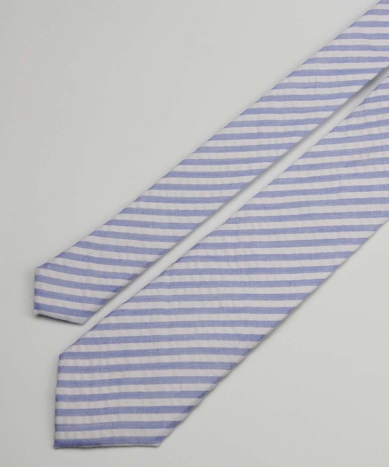 May include: A blue and white striped tie. The tie is made of a soft, textured fabric.