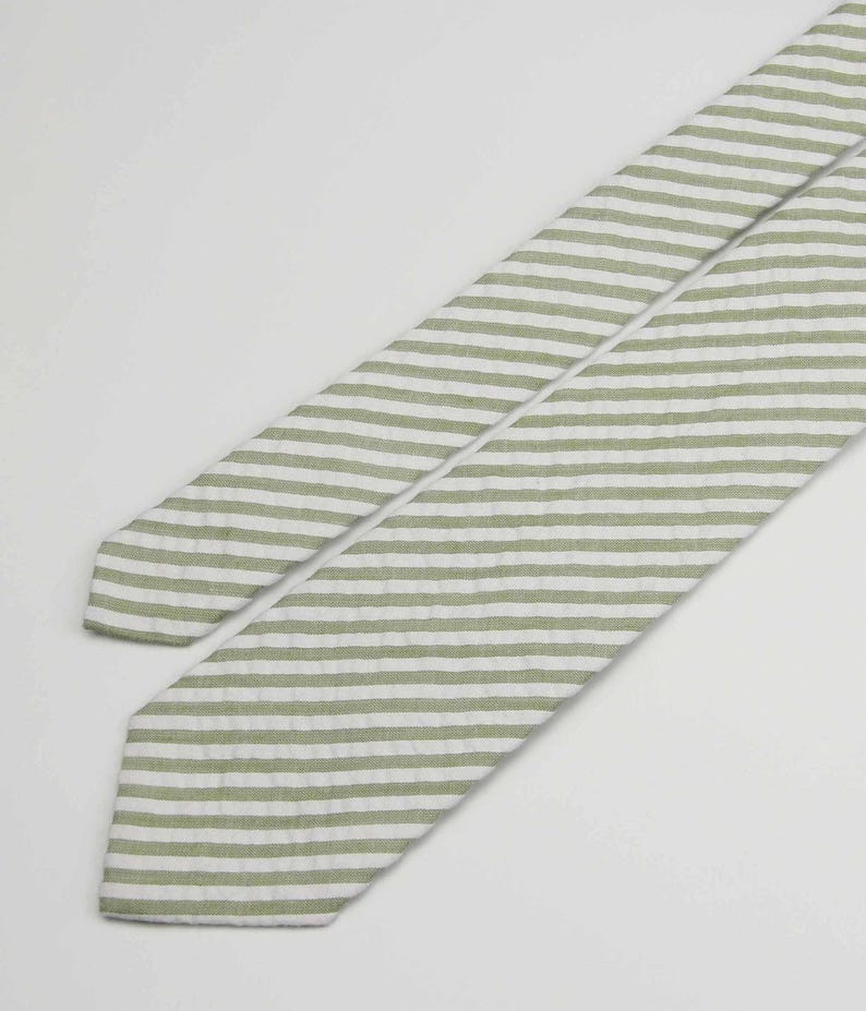 May include: A green and white striped tie. The tie is made of a soft, textured fabric.