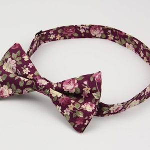 May include: A burgundy bow tie with a floral pattern featuring pink and white flowers.