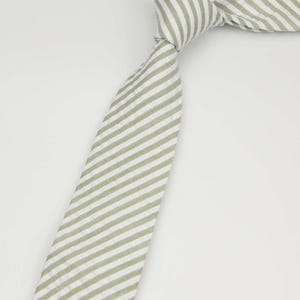 May include: A green and white striped tie. The tie is made of a soft, textured fabric.