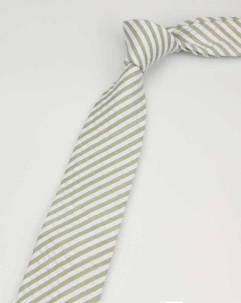 May include: A green and white striped tie. The tie is made of a soft, textured fabric.