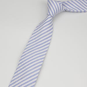 May include: A blue and white striped tie. The stripes are diagonal and the tie is made of a soft, textured fabric.