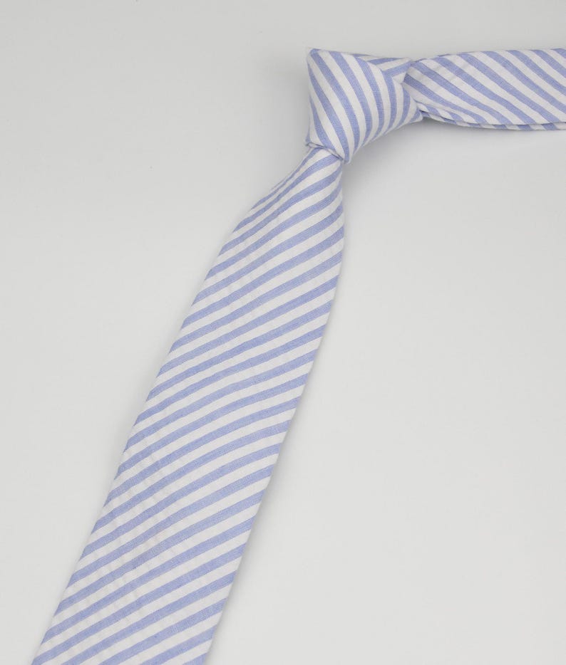 May include: A blue and white striped tie. The stripes are diagonal and the tie is made of a soft, textured fabric.