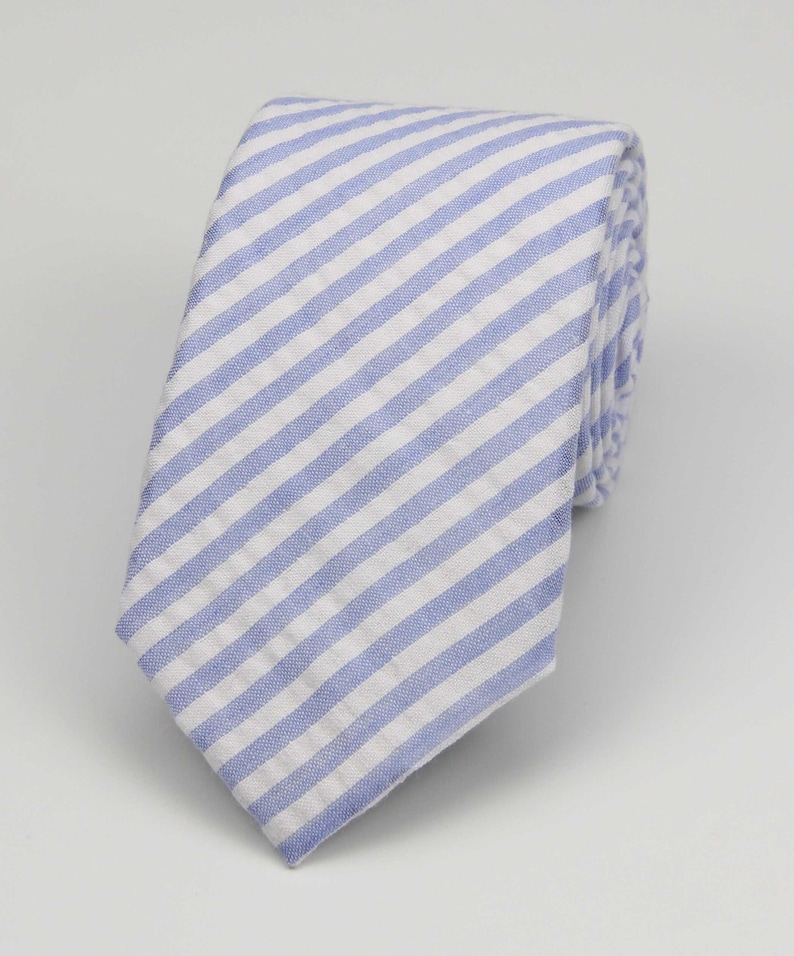 May include: A blue and white striped tie. The tie is made of a cotton fabric and has a diagonal stripe pattern.