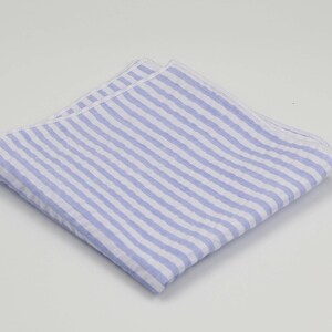 May include: A light blue and white striped pocket square. The pocket square is folded and has a white border.