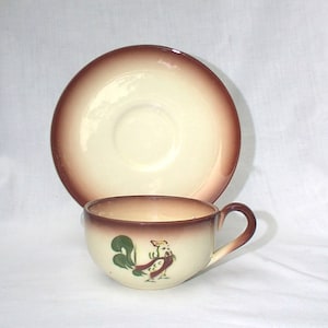 Peut inclure: Service à thé crème avec bord marron. La tasse présente un motif de coq peint à la main en vert, marron et rouge. La soucoupe est ronde avec un bord marron assorti. Un ajout classique à toute cuisine.