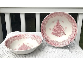 Puede incluir: Dos cuencos de cerámica blanca con un diseño de árbol de Navidad rosa. Los cuencos están sobre una superficie blanca y gris.