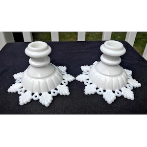 May include: Pair of white milk glass candle holders with a scalloped edge and a raised design.