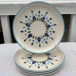 May include: A white ceramic mug with a black handle and the text "But First, Coffee" in a black, handwritten-style font. The mug is on a white surface.