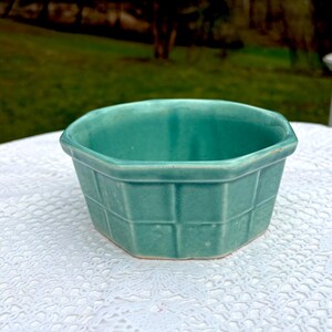 May include: A teal-colored, hexagonal ceramic bowl with a basket weave pattern. The bowl has a slightly raised rim and a smooth, glossy finish. The bowl is likely vintage and suitable for serving or display.