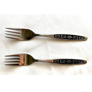 May include: Two silver forks with black handles featuring a decorative floral design.