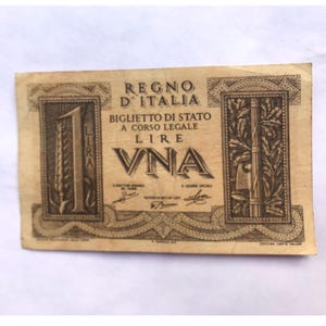 Puede incluir: Un billete de banco italiano vintage con un valor de una lira. El billete presenta un diseño marrón y blanco con el texto "REGNO D'ITALIA" y "BIGLIETTO DI STATO A CORSO LEGALE LIRE UNA".