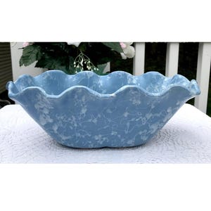 Puede incluir: Un macetero de cerámica azul claro con borde festoneado y diseño marmoleado blanco.