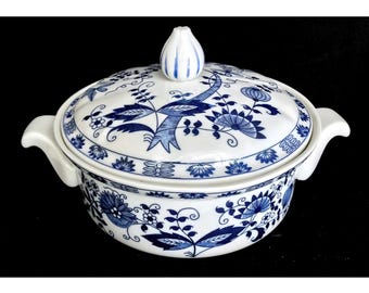 Pode incluir: Uma travessa de porcelana branca com um padrão floral azul e branco. A travessa tem uma tampa com um botão em forma de flor.