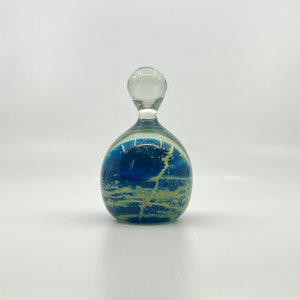 Peut inclure: Un bouchon de bouteille en verre bleu et jaune avec un dessus en verre transparent. Le bouchon de bouteille a un design en spirale.