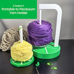 May include: A white yarn holder with two green bases. The holder has a white arm that can be raised or lowered. There are two balls of yarn on the bases, one yellow and one purple. The text "2 Tools in 1: Portable to Pendulum Yarn Holder" is in green text on a green background.