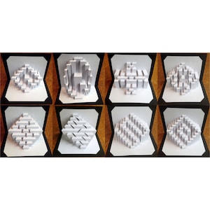 May include: Eight white paper 3D pop-up cards with geometric designs. The cards are displayed in a row on a wooden surface.