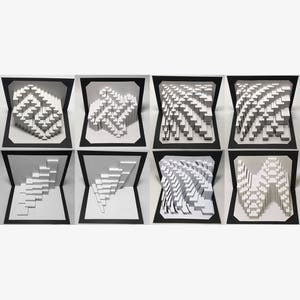 Op de afbeelding: Acht witte papieren pop-up kaarten met verschillende geometrische ontwerpen. De kaarten zijn zwart aan de buitenkant en wit aan de binnenkant.