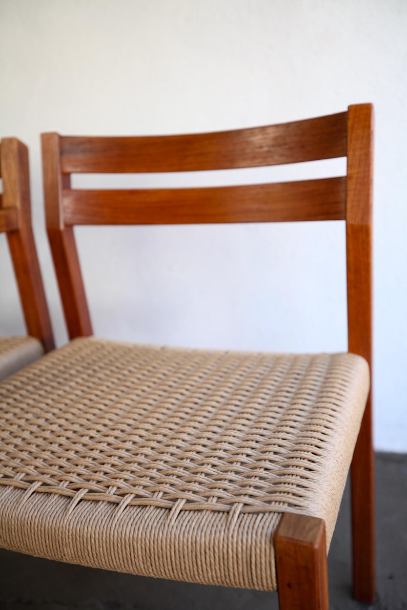 May include: Wooden chair with a woven seat. The chair has a curved back with two horizontal slats. The frame is a warm brown color, and the seat is made of a light tan woven material.