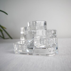 May include: A clear glass tiered organizer with multiple compartments. The organizer is designed to hold small items like jewelry, cosmetics, or other trinkets.