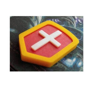 May include: A yellow and red hexagonal shaped badge with a white cross in the center.