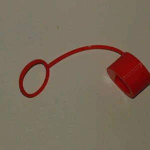 May include: A red plastic bottle cap with a loop handle.