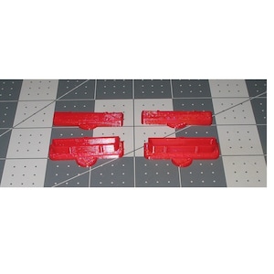 May include: Four red plastic pieces, possibly for a model or toy, on a gray and white checkered surface.