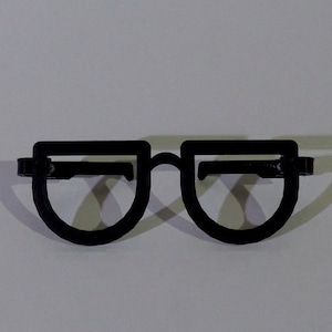 May include: Black plastic glasses with a rounded frame. The glasses are a simple design with no embellishments.