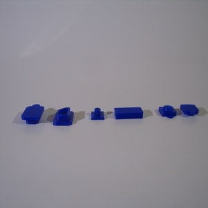 May include: A set of six blue plastic building blocks. The blocks are in various shapes and sizes, including a rectangle, a square, and a small cylinder.