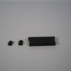 May include: Three black plastic pieces, two small and one long, likely for a 3D printer.