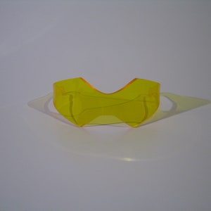 May include: A pair of yellow plastic sunglasses with a unique, angular design.
