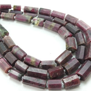 Könnte beinhalten: Eine Strähne facettierter Rubinperlen, jede Perle ist tiefrot mit grünen und weißen Einschlüssen. Die Perlen sind auf einem Silberdraht aufgefädelt.