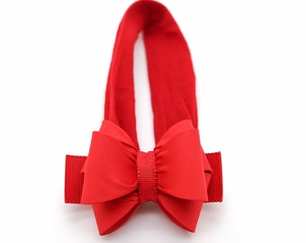 Può includere: Fascia per capelli rossa con un grande fiocco rosso. La fascia è realizzata in un materiale morbido ed elastico.
