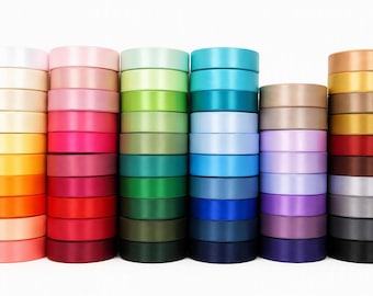 May include: A collection of six vertical stacks of satin ribbon rolls in a wide spectrum of colors, including shades of white, yellow, orange, pink, red, green, blue, purple, brown, gray, and black, arranged in a grid against a white background.
