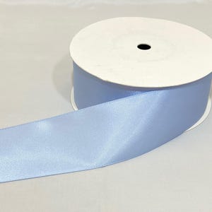 Puede incluir: Un rollo de cinta de raso azul claro. La cinta est&aacute; desenrollada, revelando una textura suave y brillante. El rollo tiene un n&uacute;cleo de cart&oacute;n blanco y cinta azul claro enrollada alrededor. Ideal para manualidades, envolver regalos y decoraciones.