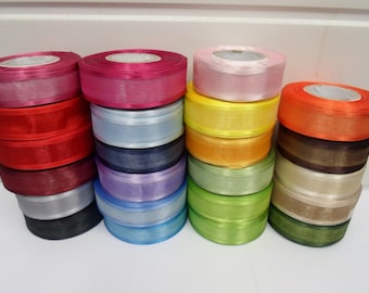 May include: Four stacks of circular ribbon spools in a variety of colors including magenta, red, dark red, gray, black, light blue, dark blue, purple, light pink, yellow, orange, brown, cream, and green. Each spool features a smooth, shiny finish.