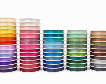 May include: Five vertical stacks of satin ribbon spools in a wide spectrum of colors including shades of yellow, orange, red, pink, purple, blue, green, brown, gray, and black. Each spool features a smooth, shiny finish and white plastic core.