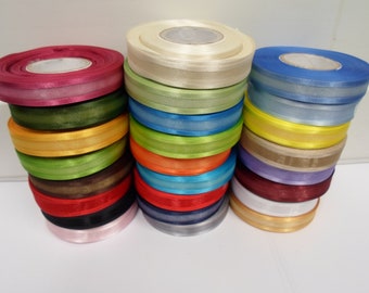 May include: Three vertical stacks of satin ribbon rolls in a wide variety of colors including magenta, olive green, yellow, lime green, brown, red, black, pink, cream, light green, blue, orange, teal, navy, gray, purple, burgundy, white, and tan.