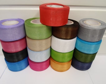 Puede incluir: Una colección de quince carretes de cinta transparente y traslúcida dispuestos en una formación apilada. Los carretes presentan una variedad de colores vibrantes que incluyen rojo, lavanda, verde lima, marrón, gris, rosa, beige, blanco, azul, negro y naranja.