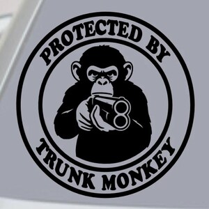 Puede incluir: Gráfico en blanco y negro de un chimpancé sosteniendo una escopeta de dos cañones, rodeado por las palabras "PROTECTED BY TRUNK MONKEY". El diseño está sobre un fondo gris.