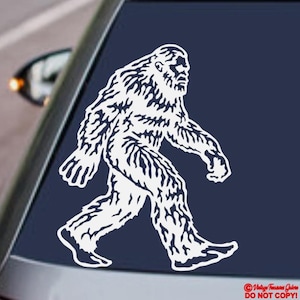 Könnte beinhalten: Weißer Vinyl-Aufkleber, der Bigfoot beim Gehen zeigt, mit detaillierter Fellstruktur. Auf einer dunkelblauen Oberfläche angebracht, wahrscheinlich einer Autoscheibe. Das Design ist eine Silhouette der legendären Kreatur.
