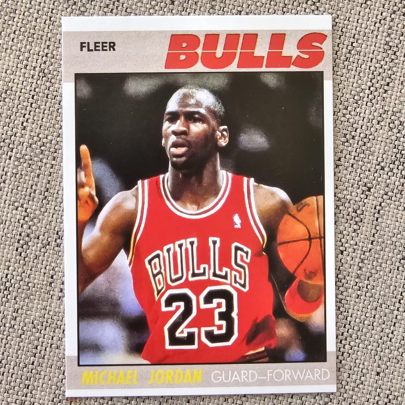 May include: A Fleer trading card featuring Michael Jordan in a red Bulls jersey with the number 23. The card has the word "Bulls" in red block letters at the top and the words "Guard-Forward" at the bottom.