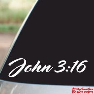 Op de afbeelding: Witte vinyl sticker met de tekst "Johannes 3:16" in een cursief schrift. De sticker is op een zwarte achtergrond.