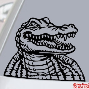 May include: Black and white alligator decal. The alligator is depicted with its mouth open, revealing sharp teeth. The design is a detailed illustration of the alligator's head and upper body, with textured skin and a menacing expression.