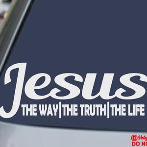 Puede incluir: Calcomanía de vinilo blanco con la palabra "Jesús" en una fuente estilizada, seguida de "THE WAY | THE TRUTH | THE LIFE" en una fuente sencilla. El adhesivo está sobre un fondo azul oscuro.