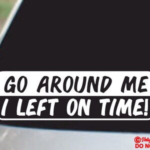 以下が含まれることがあります： 「GO AROUND ME I LEFT ON TIME!」と書かれた黒い文字の白いビニールステッカー