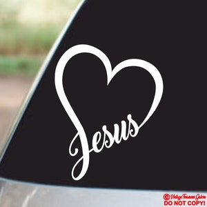 May include: White vinyl decal of a heart with the word "Jesus" inside. The decal is on a black background.