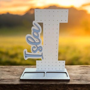 May include: White wooden earring holder shaped like the number one with the word "I am" written on the side. The holder has a blue background and white polka dots. The base of the holder has the text "I am beautiful. I am strong. I am smart. I can count. I am enough."