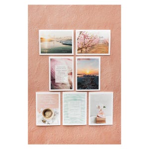 May include: A collection of seven framed art prints with inspirational quotes and scenic images. The prints feature photographs of a sunset, ocean waves, and flowers. One print includes a cup of coffee. The prints are arranged on a pink background.