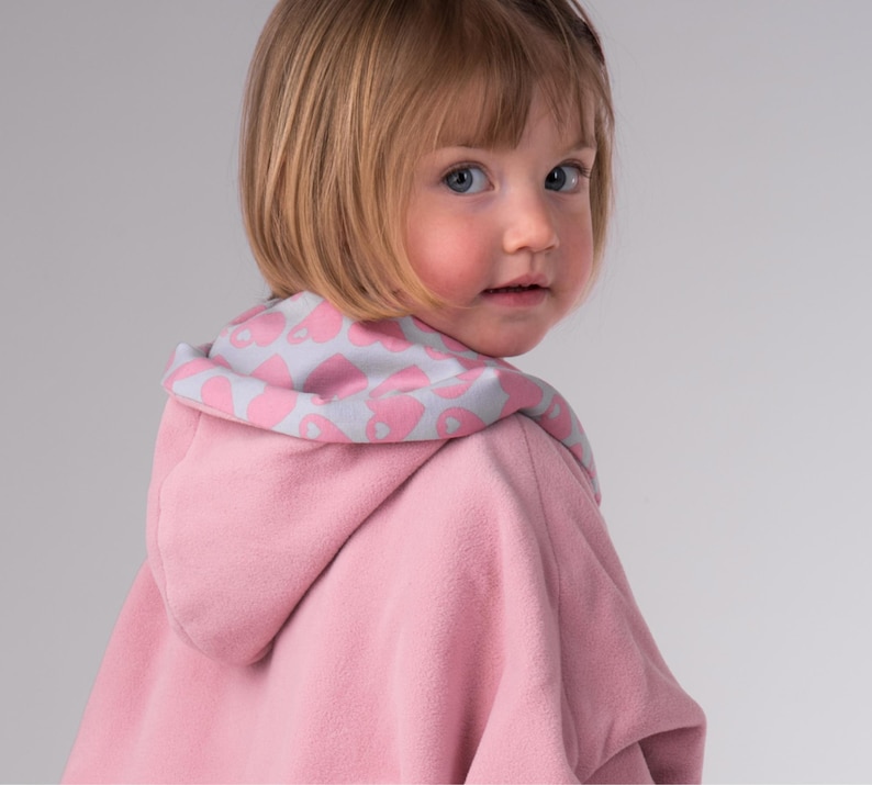 Nahaufnahme seitlich, Kind trägt rosa Mara Poncho mit herzgefütterter Kapuze, Kinder Poncho PDF Schnittmuster